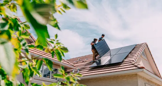 men installing solar panels on the roof of a home