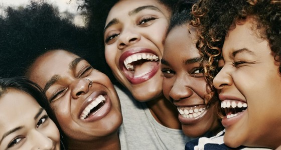 A group of black girlfriends hug and laugh