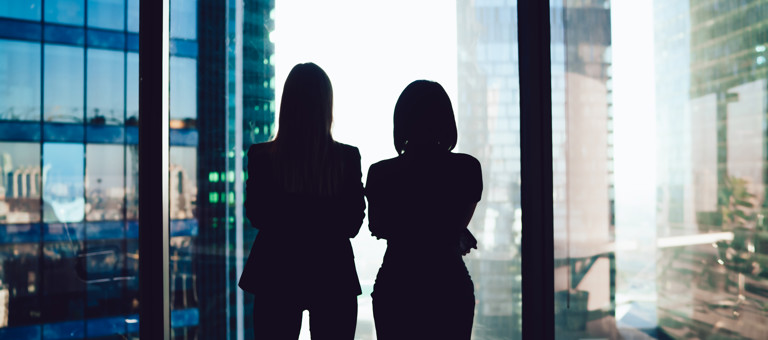 Two women looking out a window at high rise buildings