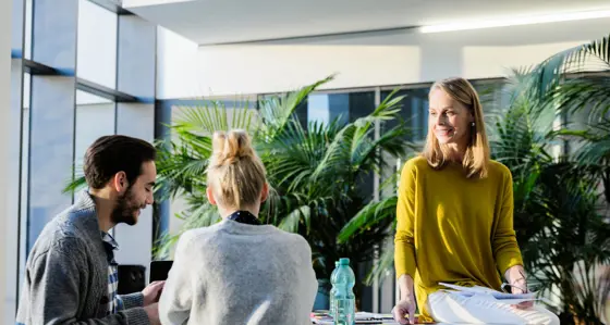 People around a table chatting with a large plant behind them