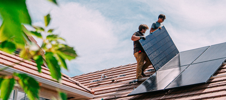 Workers installing a solar panel on a roof