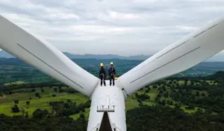 Two workers on top of a wind turbine