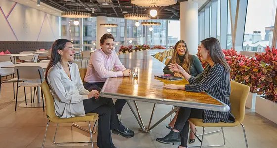 Four laughing and smiling colleagues sitting in an relaxed office environment