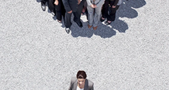 An aerial view of a group dressed in suits with one person alone in front