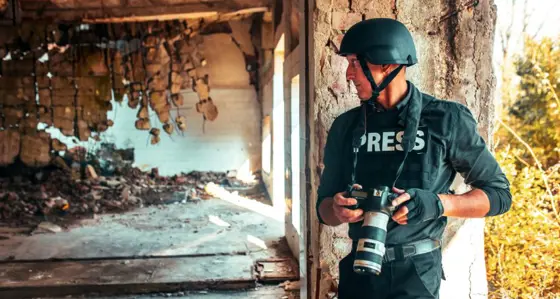 Man in press uniform taking photos in conflict