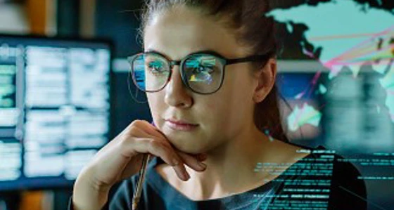 A woman looking thoughtful in front of multiple computer screens