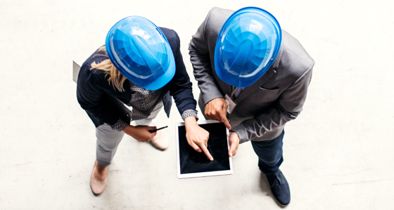 2 people in hard hats holding tablet