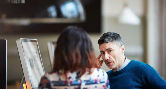 Man and woman talking in front of computers