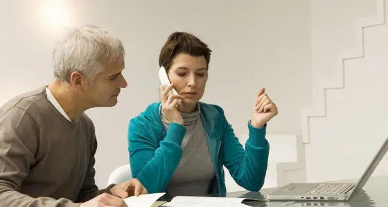 Two people looking at bills and calling on the phone