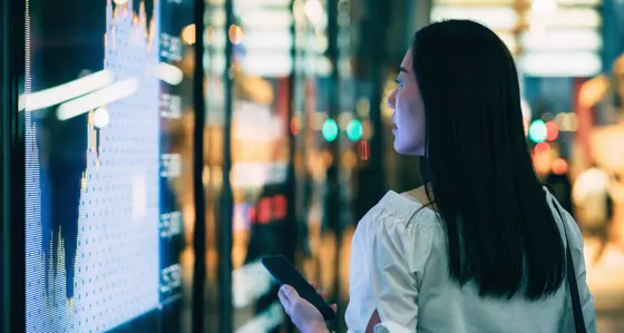 A woman holding her phone while looking at data on her phone