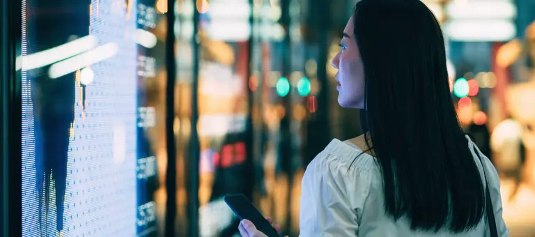 A woman holding her phone while looking at data on her phone