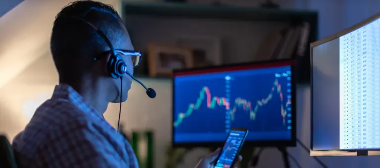 Man looking at charts on his phone and computer