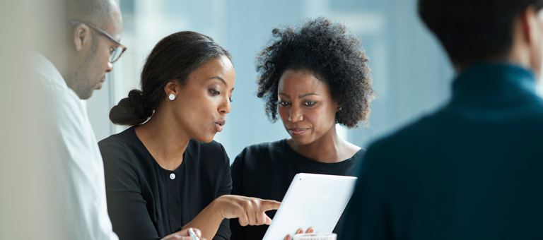 Group of co-workers standing around a desk and having a meeting