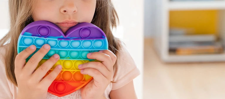 Child holding a rainbow coloured heart