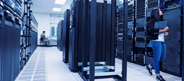 A man sitting and a woman walking in a data centre